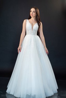 Uzun saçlı ve makyajlı beyaz gelinlikli güzel bir kadın. 