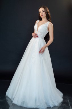 Gri stüdyo arka planında poz veren gelinlik içindeki güzel genç gelin. 