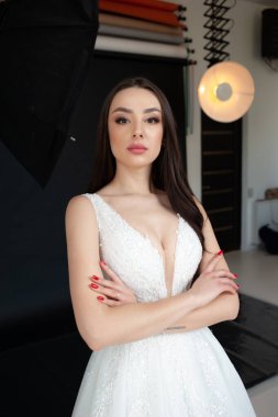 Genç ve güzel gelin beyaz bir odada poz veriyor.