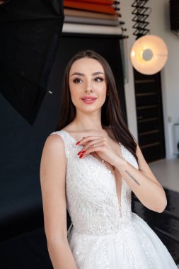 Beyaz elbiseli, dantel elbiseli, güzel esmer gelin stüdyoda poz veriyor. güzellik moda konsepti.
