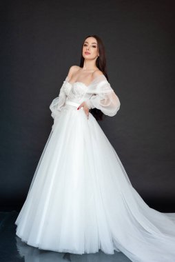 Gri arka planda beyaz elbiseli güzel gelin.