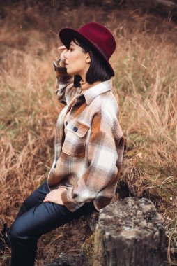 Çam ormanında şapkalı güzel bir kız ve ceket. 