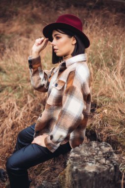 Sonbahar ormanında poz veren şapkalı kadın. 