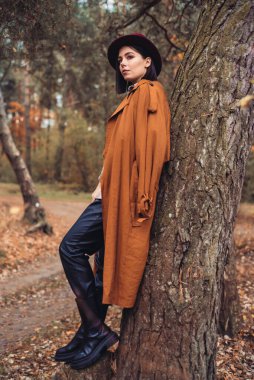 Sonbahar ormanında şapkalı ve deri ceketli bir kadın. 