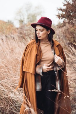 Genç kadın sonbahar ormanında şapkasıyla poz veriyor. 