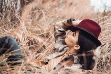 Kız sonbahar ormanında oturuyor. 