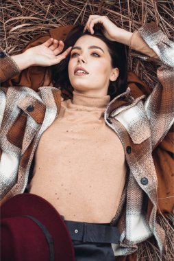 Genç ve şık hippi kız kahverengi arka planda yalnız poz veriyor. 