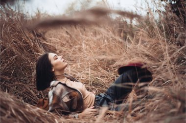 Genç bir kadın sonbahar ormanında çimlerde yatıyor. 