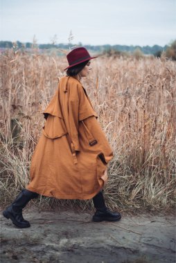 Sonbaharda kırmızı ceketli ve şapkalı bir kadın tarlada duruyor.. 