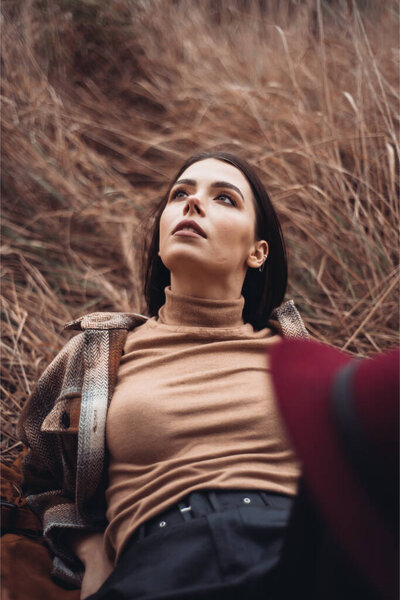 portrait of young attractive girl in brown sweater posing in forest 