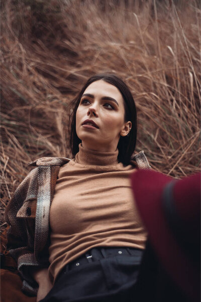 young beautiful stylish woman in brown sweater in autumn forest 
