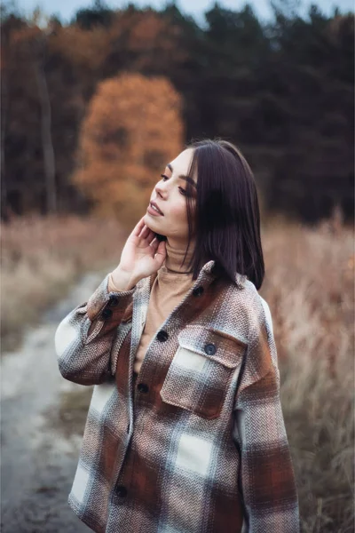 暖かいセーターとジーンズを着た秋の森の中の美しい若いスタイリッシュな女の子 — ストック写真