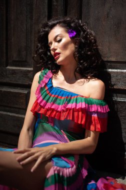 Genç, güzel, esmer, kırmızı elbiseli, yeşil duvar arkasında poz veren bir kadın. Yaşam tarzı insanların yakın çekim kavramı. 