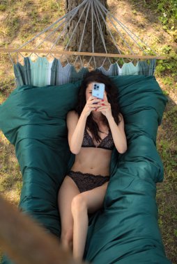 Siyah mayo ve bikinili kadın yazın hamakta güneşleniyor. 