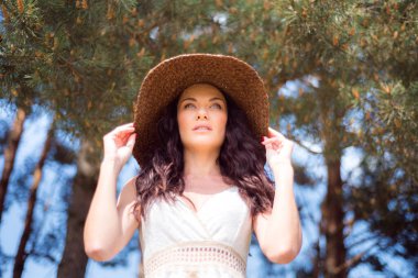 Güneşli bir parkta poz veren yazlık elbiseli güzel bir kadın. 