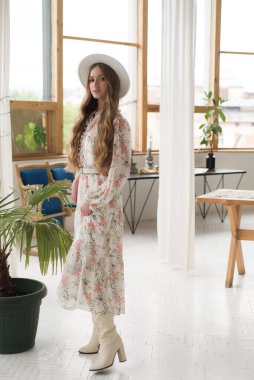 Beyaz elbiseli ve şapkalı kadın stüdyoda. 