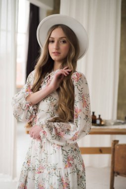 Stüdyoda beyaz elbiseli ve hasır şapkalı güzel sarışın kız. 