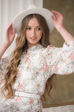 Beyaz elbise ve şapkayla poz veren güzel genç bir kadın. 