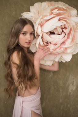 Genç, güzel, kıvırcık saçlı, beyaz çiçekli poz veren esmer bir kadın. 