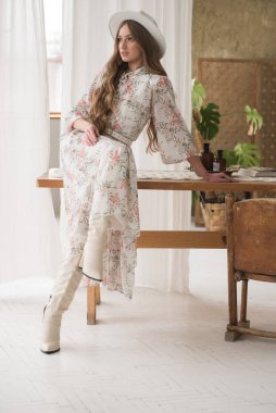 Beyaz gömlekli ve eski bir pencerenin yanında poz veren güzel bir genç kadın. moda tarzı 