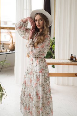 Beyaz elbiseli, klasik şapkalı genç bir kadın. 