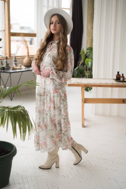 İç kısımda çiçekli bir elbise giymiş güzel genç bir kadın. 