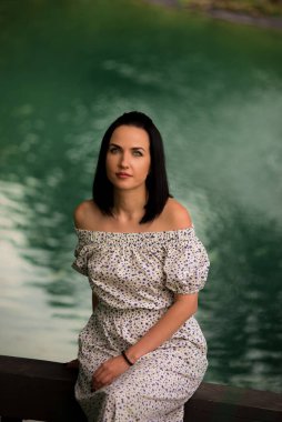 Gölün arka planında beyaz elbiseli güzel bir esmer.