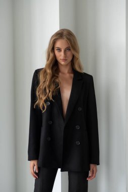 Beyaz arka planda siyah takım elbiseli güzel bir kız.