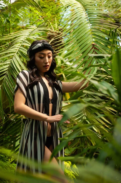 a woman in a striped dress standing in a jungle