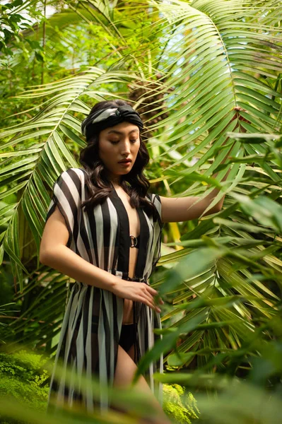 a woman in a bikini and a hat in a jungle