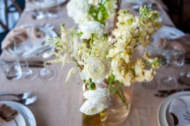Düğünde ya da akşam yemeğinde ahşap masada çiçekler ve çatal bıçaklarla güzel bir masa.