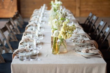 Düğünde ya da akşam yemeğinde ahşap masada çiçekler ve çatal bıçaklarla güzel bir masa.