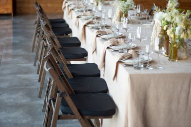 Düğünde ya da akşam yemeğinde ahşap masada çiçekler ve çatal bıçaklarla güzel bir masa.