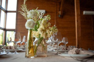Düğünde ya da akşam yemeğinde ahşap masada çiçekler ve çatal bıçaklarla güzel bir masa.