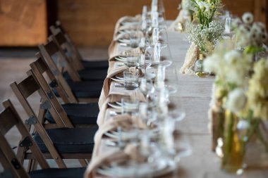 Düğünde ya da akşam yemeğinde ahşap masada çiçekler ve çatal bıçaklarla güzel bir masa.