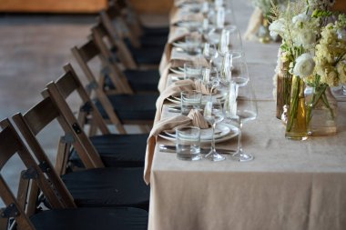 Düğünde ya da akşam yemeğinde ahşap masada çiçekler ve çatal bıçaklarla güzel bir masa.