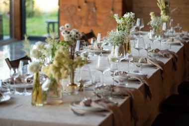 Düğünde ya da akşam yemeğinde ahşap masada çiçekler ve çatal bıçaklarla güzel bir masa.