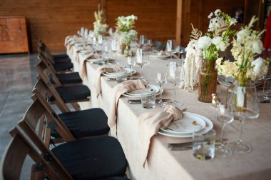 Düğünde ya da akşam yemeğinde ahşap masada çiçekler ve çatal bıçaklarla güzel bir masa.