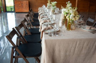 Düğünde ya da akşam yemeğinde ahşap masada çiçekler ve çatal bıçaklarla güzel bir masa.