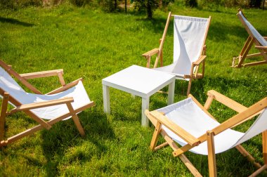 Parktaki yeşil çimlerin üzerinde katlanan boş sandalyeler..