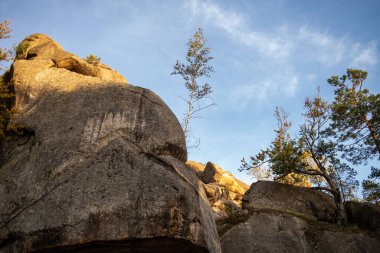 Dağlardaki kayalar. Mavi gökyüzü ve ağaçlar