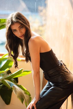 Siyah saçlı ve siyah makyajlı çekici bir kadının portresi evde poz veriyor.