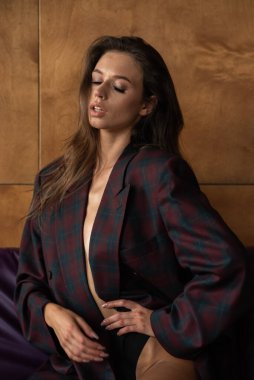 Siyah ceketli ve gömlekli seksi kadın stüdyoda poz veriyor.