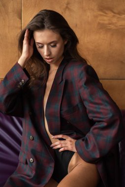 Seksi iç çamaşırı ve ceketle poz veren genç bir kadın.