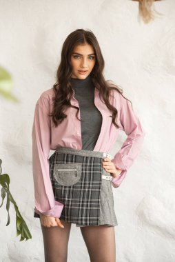 Moda portresi moda pembe ceketli güzel bir kadın duvarın yanında poz veriyor.