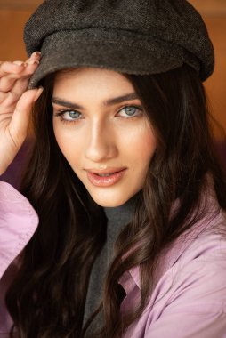 Bereli ve bereli genç bir kadın sonbahar yapraklarında poz veriyor.