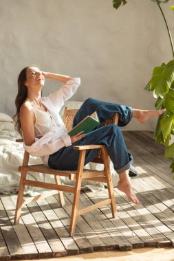 Beyaz gömlekli, mavi kotlu, beyaz tahta sandalyeli, kıvırcık saçlı genç bir kız..