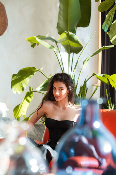 young woman with dark hair and bright makeup in a white dress with a glass of wine.