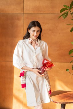 Beyaz elbiseli güzel bir kadın elinde çiçeklerle