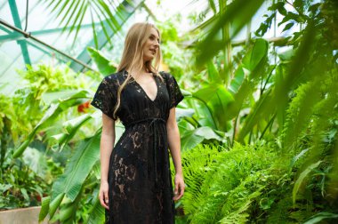 Tropik tatil köyünde yazlık giysiler giyen güzel genç bir kadın.